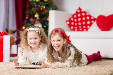 Noel, Noel, Noel, kış, mutluluk konsepti - tabletle oynayan iki sevimli kıvırcık kız