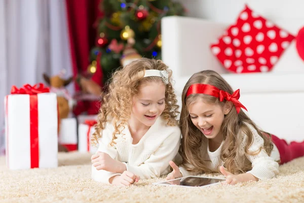 Christmas, x-mas, winter, happiness concept - two adorable curly girls playing with tablet pc — Stock Photo, Image