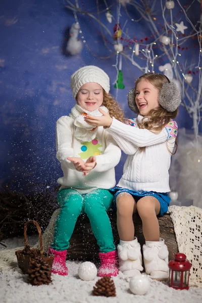 Winter concept: portrait of two adorable happy girls wearing warm closing and playing with snowflakes — Stock Photo, Image