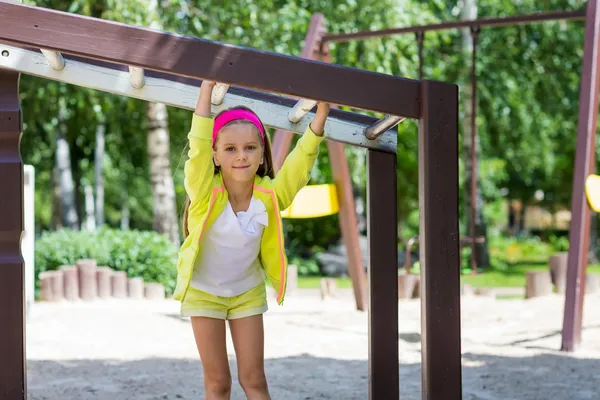 Klein meisje speelt in een speeltuin — Stockfoto