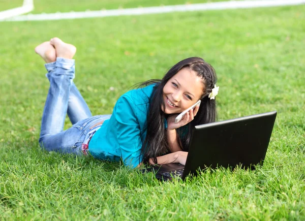 Jovem deitada usando um laptop — Fotografia de Stock