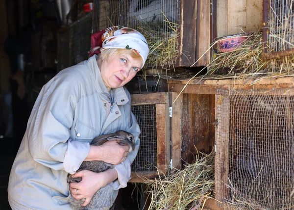 Mulher cuida dos coelhos na fazenda — Fotografia de Stock