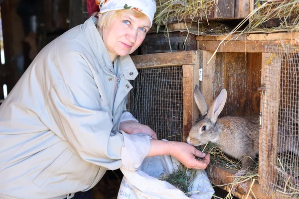 Mulher cuida dos coelhos na fazenda — Fotografia de Stock