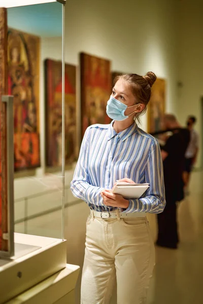 Mulher visitante vestindo uma máscara antivírus no museu histórico olhando para fotos. — Fotografia de Stock