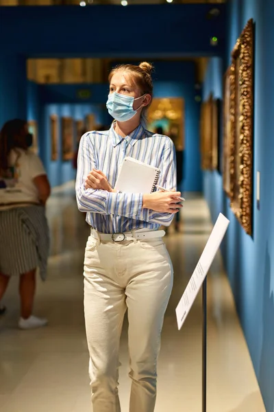 Mulher visitante vestindo uma máscara antivírus no museu histórico olhando para fotos. — Fotografia de Stock