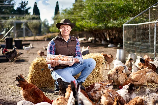 Stolzer junger Mann mit einem Korb voller Eier mit Hühnern hinter sich. — Stockfoto