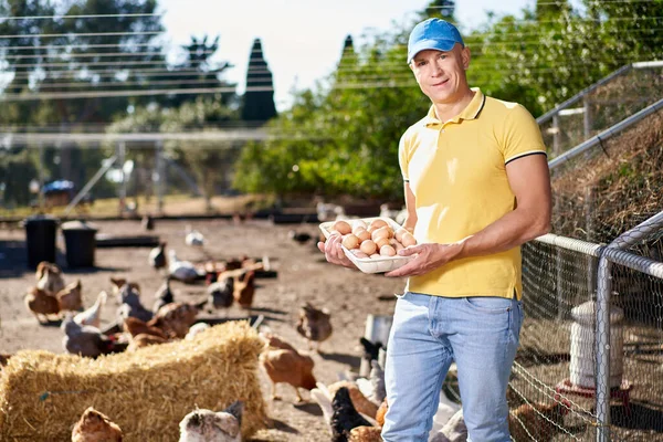 그 뒤에 닭과 달걀으로 채워진 바구니를 들고 자랑 스럽게 젊은 남자. — 스톡 사진