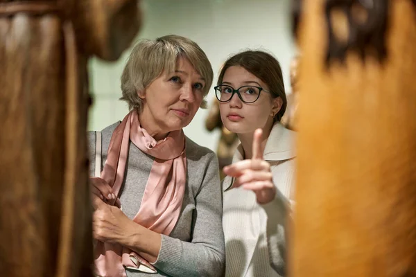 Menina com mulher olhando com interesse para objetos de arte sob vidro no museu — Fotografia de Stock