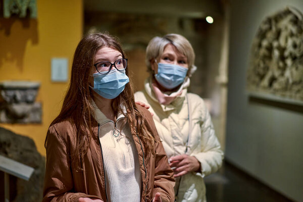Protection from the virus. A tourist visits the sights of the Museum in a medical mask. People and pictures in the background. The concept of a viral pandemic and maintaining distance Stock Photo