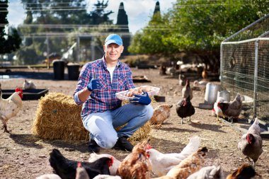 Çiftçi çiftlikte tavuk yumurtası gösteriyor.