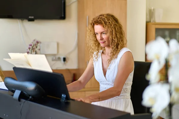 Woman in white dress sitting at the piano. Woman playing piano were digitally modified. Practice at home.