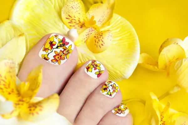 Pedicure met gele orchideeën. — Stockfoto