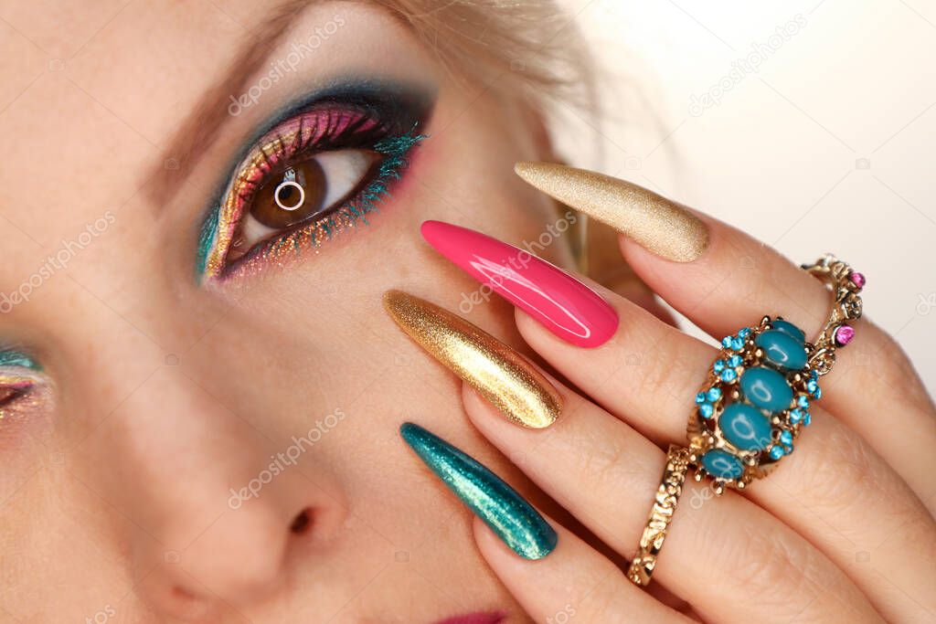 A model with pink turquoise makeup and nail design with jewelry.