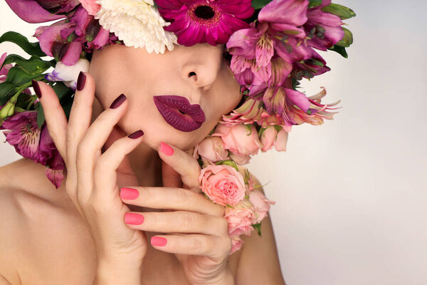 Burgundy pink manicure and makeup on a woman with a variety of flowers.