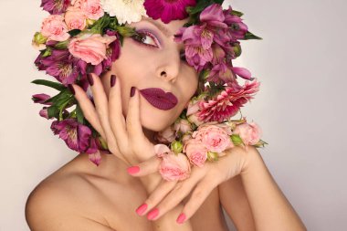 Çeşitli çiçekleri olan bir kadına Burgundy pembe manikür ve makyaj.