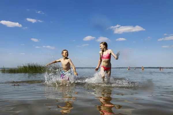 夏は湖で男の子と女の子が遊ぶ ストック写真