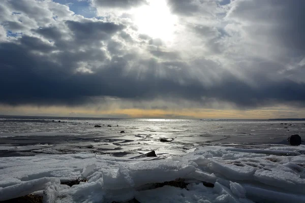 Soleil à travers les nuages orageux à la mer gelée Image En Vente