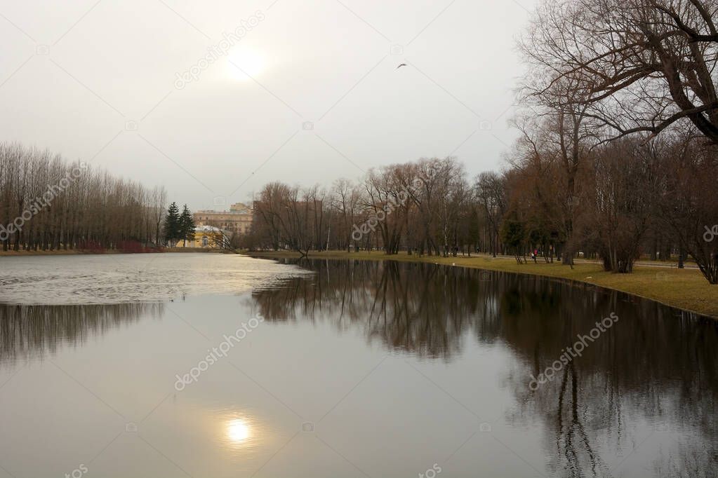 Sunset in Victory Park, reflection of the sun in the pond. Russia, St. Petersburg, early spring. Victory Park - the largest mass grave in Europe