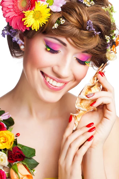 Jeune femme avec un maquillage glamour lumineux et des fleurs — Photo