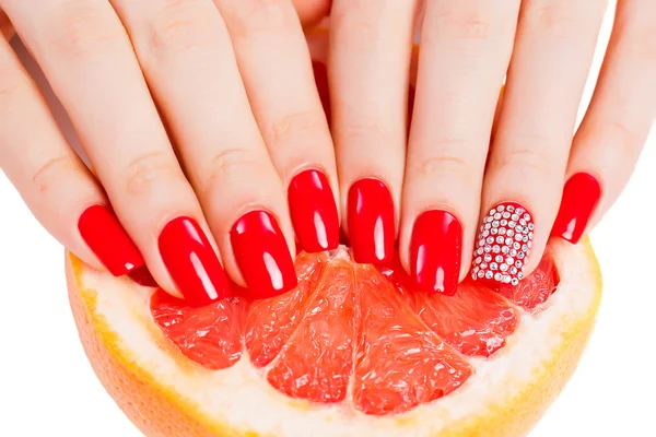 Hände mit roten Nägeln liegen auf Grapefruit — Stockfoto