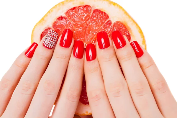 Las manos con las uñas rojas yacen sobre el pomelo — Foto de Stock