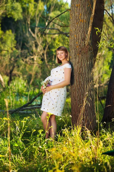 Giovane donna incinta con fiori all'aperto — Foto Stock