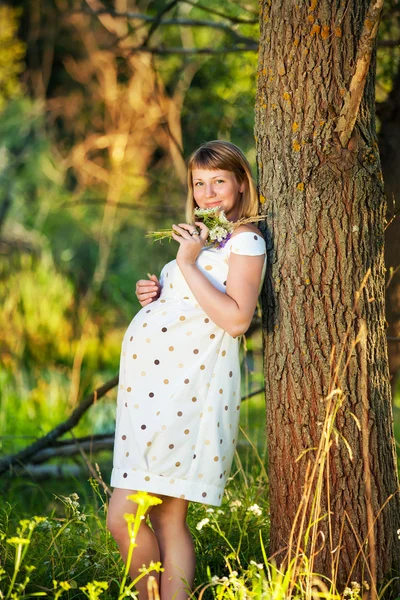 Mujer embarazada joven con flores al aire libre — Foto de Stock