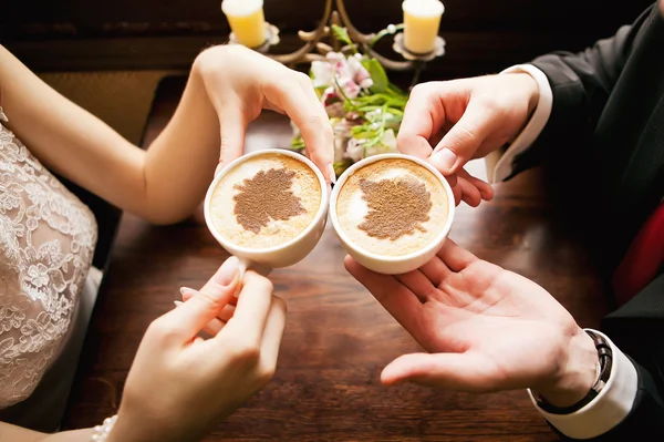 Bruid en bruidegom handen met koffie cups — Stockfoto