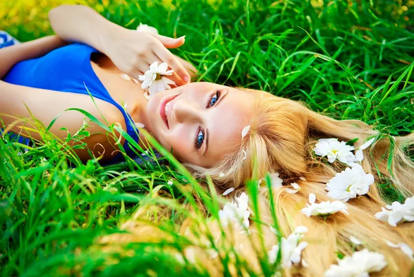 Femme couchée dans l'herbe verte avec des fleurs en poils — Photo