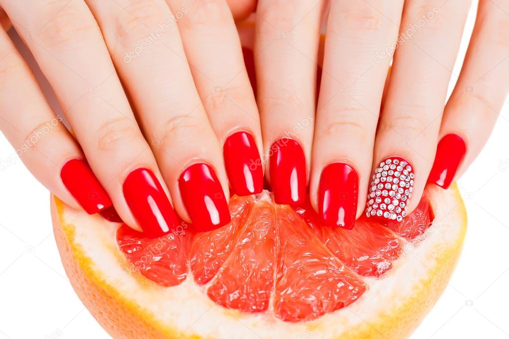 Hands with red nails lie on grapefruit