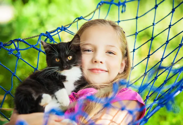 Chica se encuentra en una hamaca con un gato al aire libre — Foto de Stock