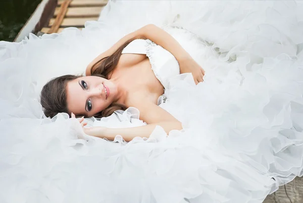 Wunderbare zarte Braut liegt im Brautkleid — Stockfoto