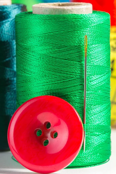 Green spool of thread with needle and button — Stock Photo, Image