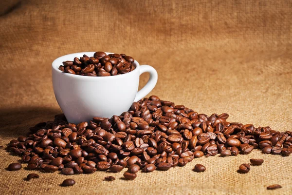 Kaffe kopp och arabica bönor på duk säck — Stockfoto