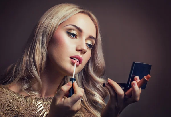 Mujer joven aplicando lápiz labial mirando al espejo — Foto de Stock