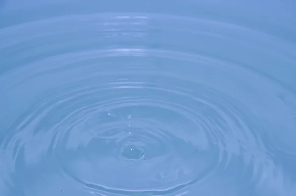Kapka vody, modré vody pozadí — Stock fotografie