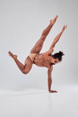 Handsome sporty black guy dancing on a gray background.