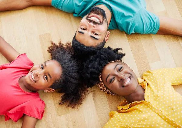 Child daughter family happy mother father floor lying down fun together girl cheerful group team teamwork home black — Stock Photo, Image