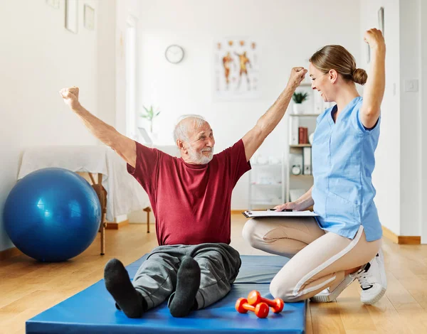 Nurse doctor senior care exercise physical therapy exercising help assistence happy strong physiotherapy strech band clinic therapist elderly man — стоковое фото