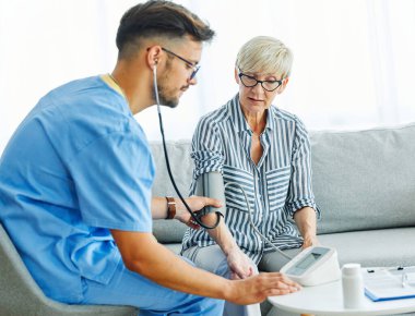 Hemşire doktor kıdemli bakıcı, muayene tansiyonunu ölçmeye yardım ediyor. Nabız, emeklilik evi steteskop, yaşlı erkek, kadın sağlığı hemşiresi.