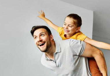 Çocuk kız, aile, mutlu baba, sırtımda oynaşıyor. Neşeli kız, evde gülüyor, birbirine bağlanıyor.