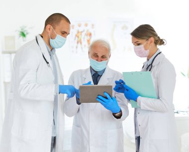 Doktor hastane sağlık hemşiresi ile görüşüyor. Sağlık ekibi maskeli kadın tablet erkek virüs koruma ekibi.