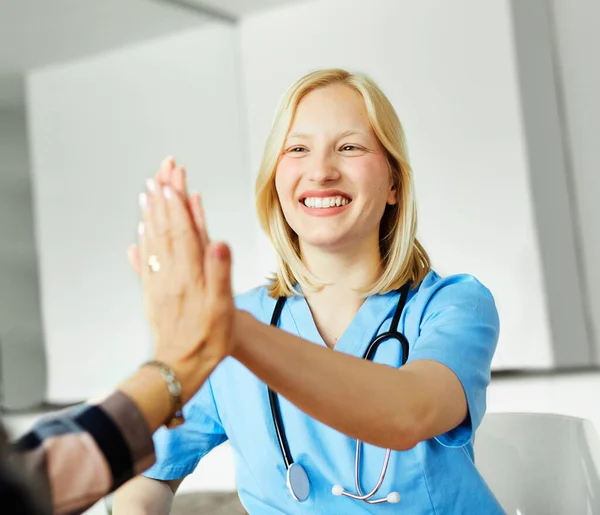 Portrait of a young female nurse givinh high five to patient