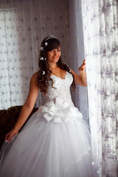 Bride brunette woman standing at the window in the room on the w — Stock Photo, Image