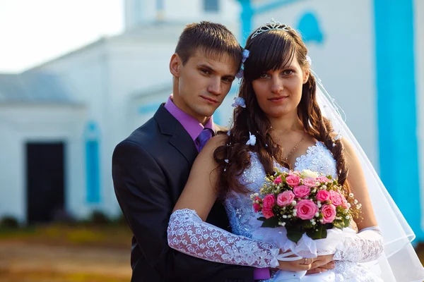 Couple man and woman at wedding next to church on blue backgroun — Stock Photo, Image