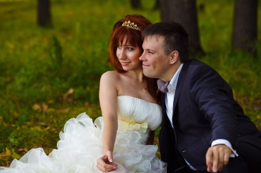 Kızıl saçlı gelin ve damat, yeşil kutusunda çimenlerin oturmuş, düğün