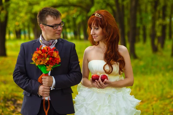 Bride and groom stand on a green background in forest, red haire — Stock Photo, Image