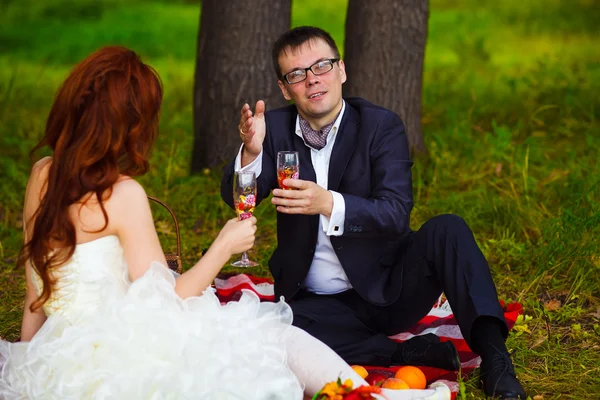 Bride redhead and groom wedding in green field sitting on picnic — Stock Photo, Image
