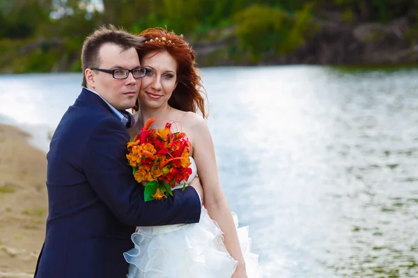 Recién casados novia y novio de pie junto al río — Foto de Stock