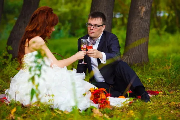 En Rusia pareja novia y novio sentado en la hierba verde, un picni — Foto de Stock